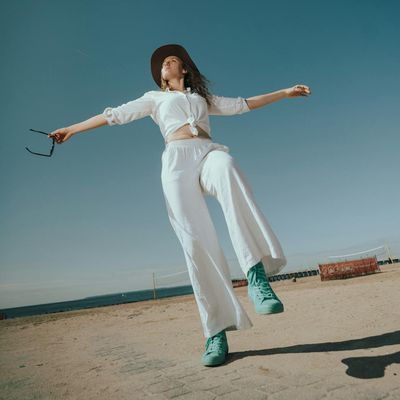 A person in a fluid warrior yoga pose, seen from a low angle.